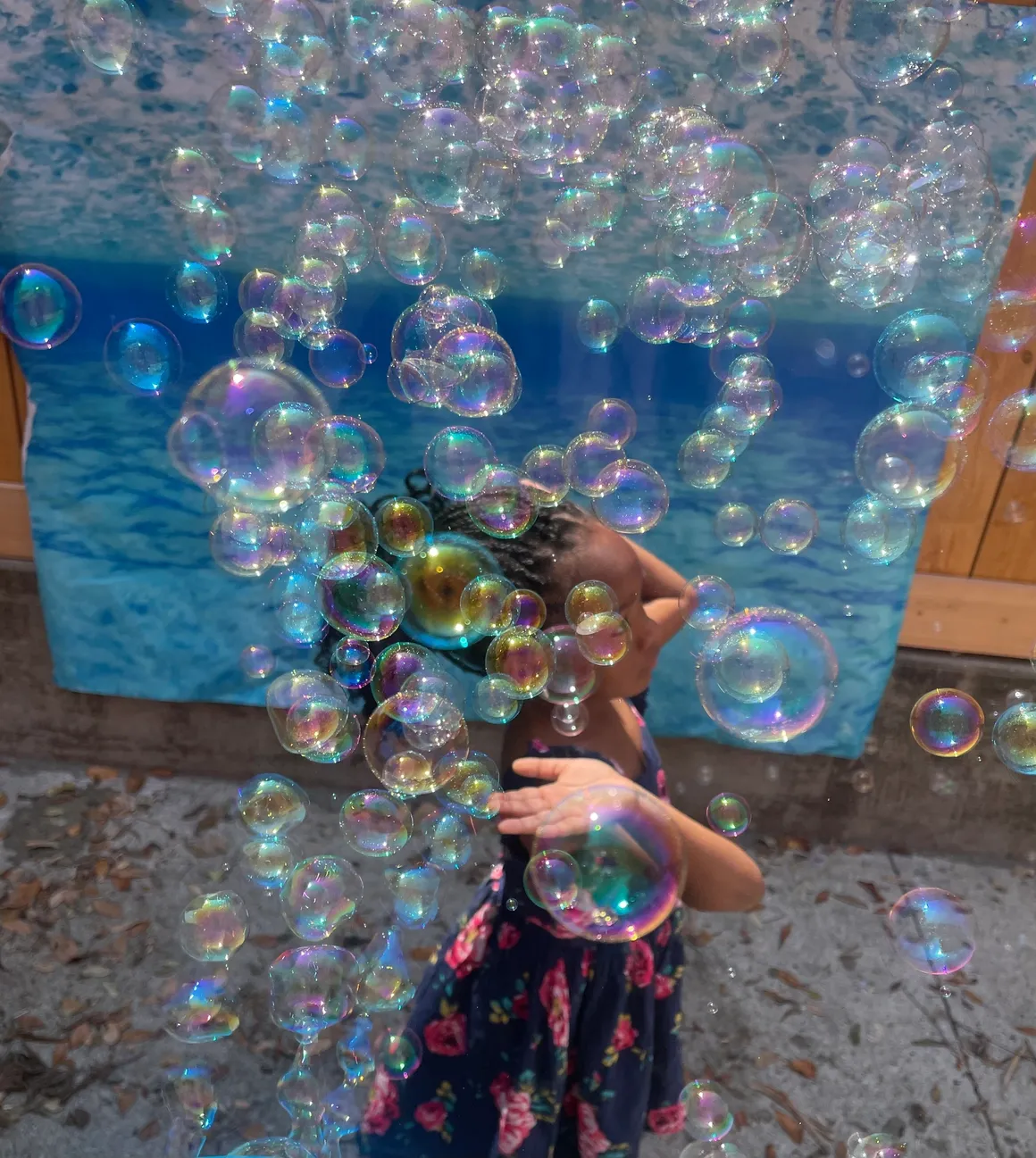 A girl is blowing bubbles in front of the ocean.