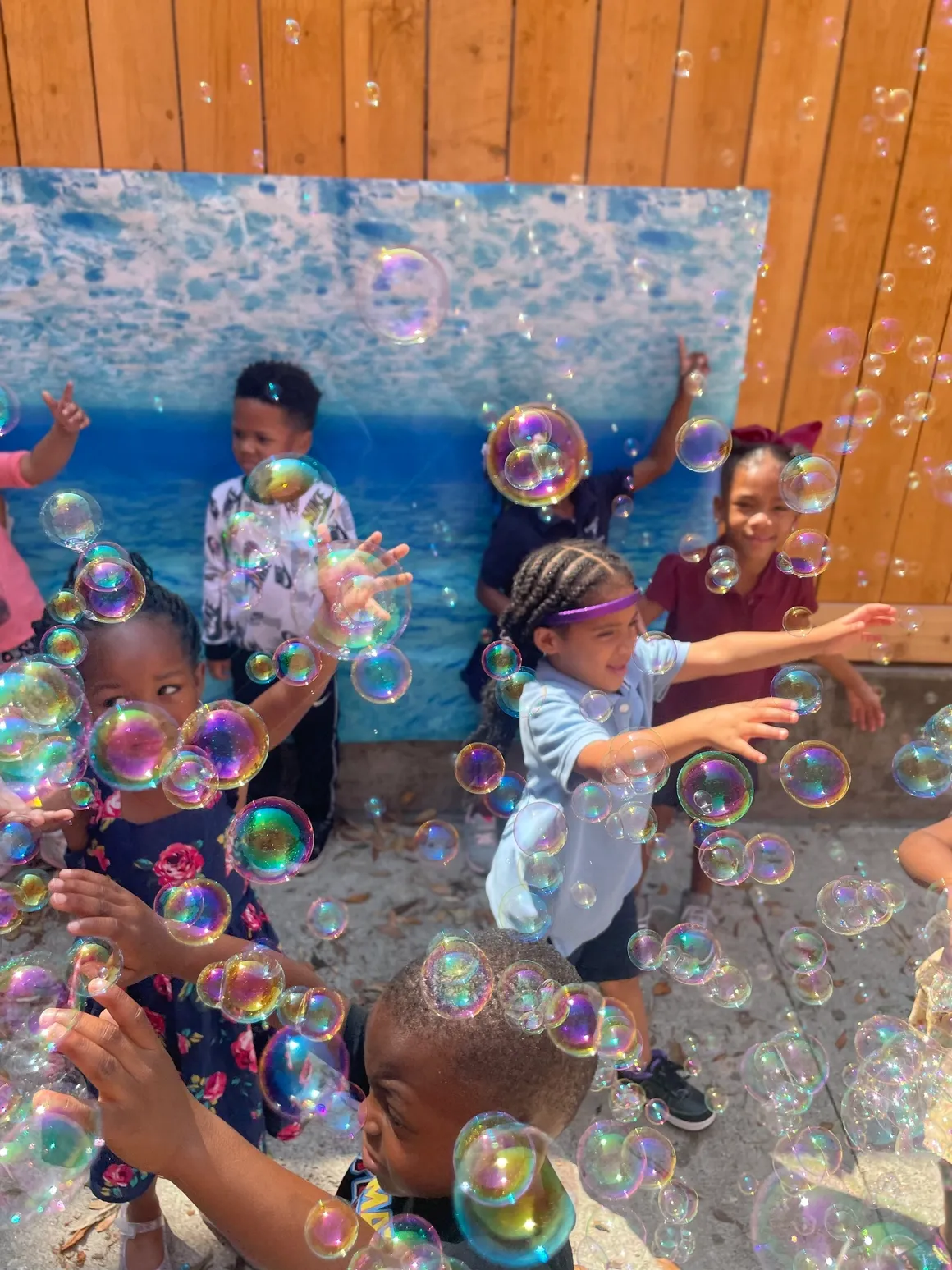 A group of people playing with bubbles in front of a mural.