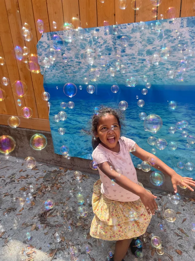 A little girl standing in front of some bubbles
