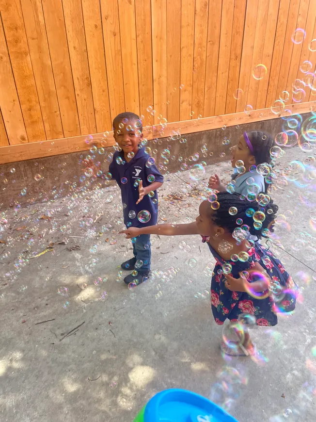 Two children playing with bubbles in a yard.
