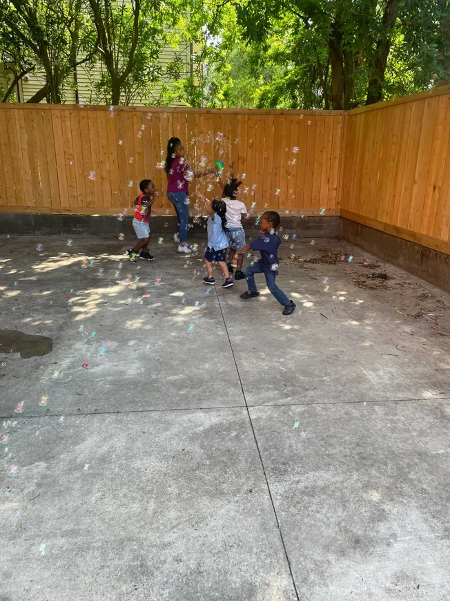 A group of children playing with bubbles in the yard.