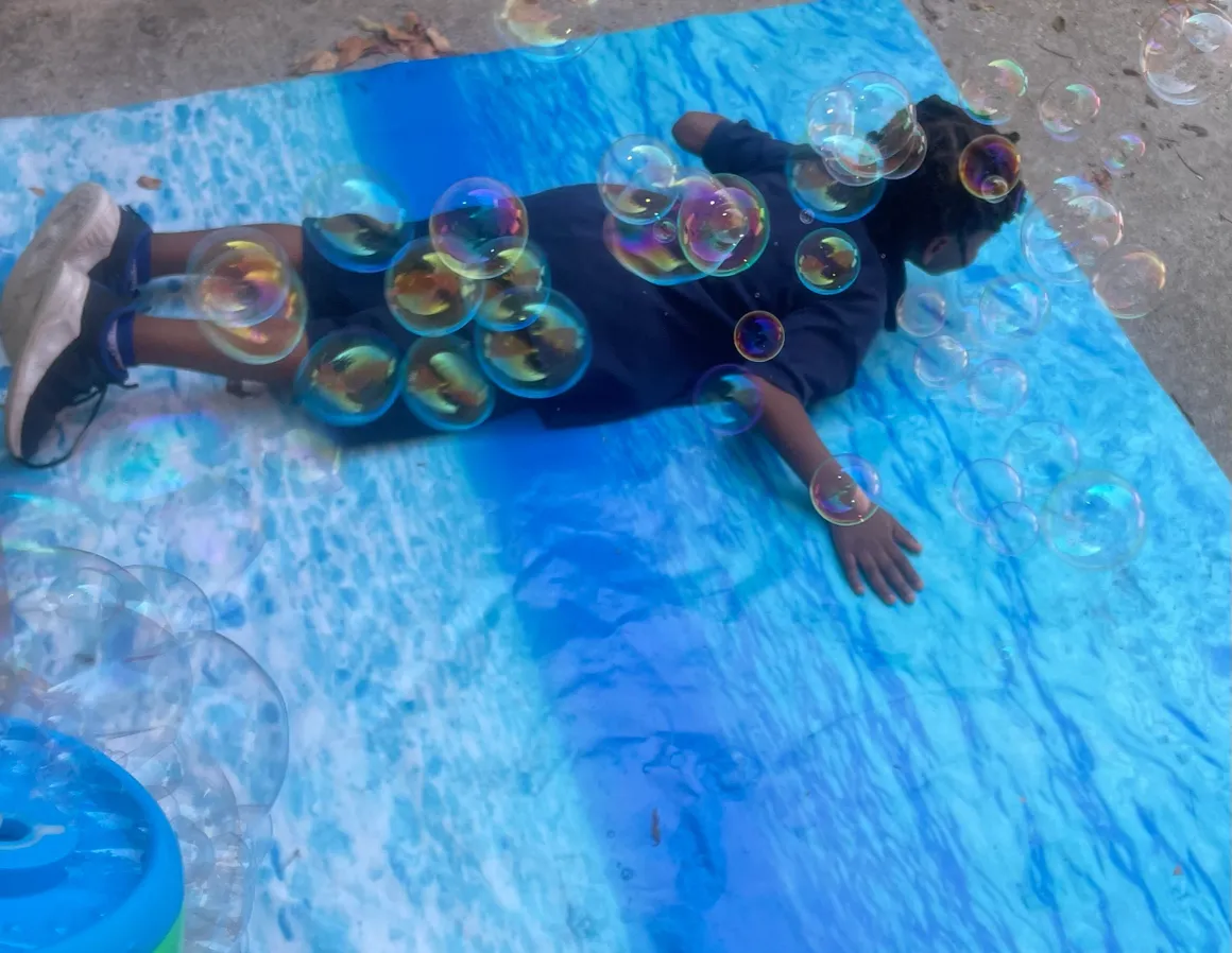 A person laying on the ground with bubbles in their eyes.