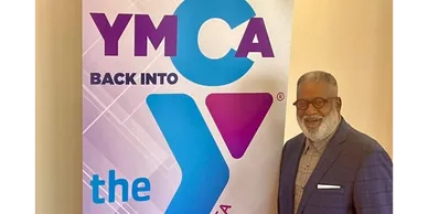A man standing in front of a ymca sign.