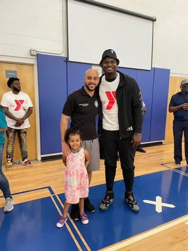 A man and child pose for a picture with a basketball player.