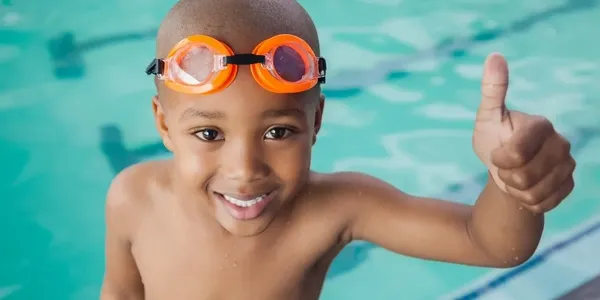 A young boy with goggles in the pool.