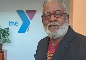 A man with a beard and glasses in front of the ymca logo.