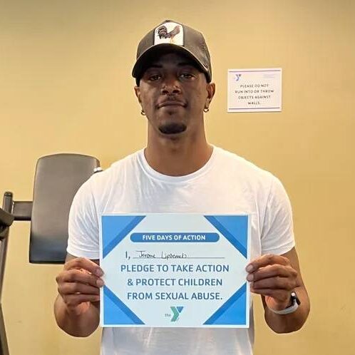 A man holding up a sign that says please to take action and protect children from sexual abuse.
